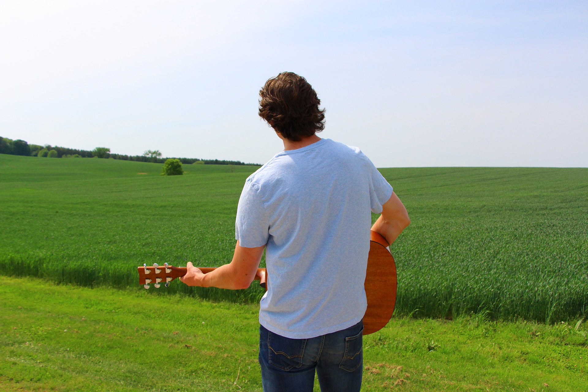 Basil standing in a field playing his guitar